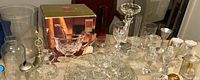 Photo showing a variety of clear cut glass and crystal items including boxed Essex lead crystal gravy bowl with ladle, clear cut glass platter, various glassware including candle holders, shakers, vases, and pitchers.