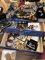 Image showing the overall 2-drawer blue box open with many costume jewelry pieces including necklaces, pins, bracelets, earrings, cuff links, and coins.