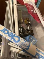 View from above showing white metal brackets, blue box labeled 'Clear', door handles, and assorted hardware in plastic container