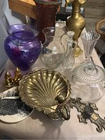 Photo showing the entire assortment of home decor items on a table including vases, candle holders, salt and pepper shakers, a brass door pull, and a decorative metal cross.