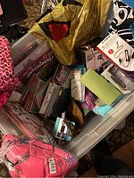 Photo showing a mix of new toys, boxed items, and electronic accessories inside a plastic container.