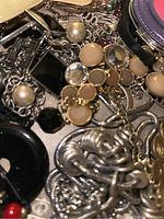 Close-up photo of assorted jewelry showing various bead styles, faux pearls, and metal links.