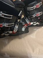 Photo showing one black ski boot with three silver metal adjustable buckles with red accents, size 10.