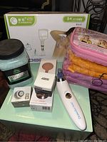 Full view of lot items including facial collagen stimulator device, derma suction device, Chinese suction cupping set box, jars, and gloves