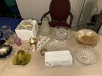 Wide view of all glassware and decorative items including iridescent amber bowls and plates, clear green candy dish, ceramic angels, Leonard silver plate bowls, and other pieces.