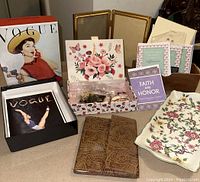 Photo of vintage decorative boxes, costume jewelry, embossed leather notebook, faith quote booklets, Vogue collectible cards, and a floral ceramic tray