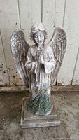 Front view of garden angel statue showing praying position and flower details on base