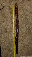 Full length view of the walking stick with measuring tape showing approximately 36 inches long on carpeted floor.