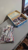 Photo showing a blue storage box filled with hockey cards, alongside a loose stack of cards on a table.
