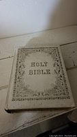 Photo of the front cover of the vintage Holy Bible showing ornate border and title in old-style font.