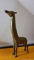 Front-right angled view of vintage Indian brass giraffe figurine showing detailed engraved giraffe pattern and shape.