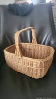 Front angle view of the rectangular wicker basket showing handle and woven body.