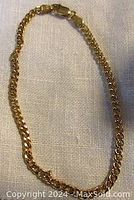 Full view of the 10K yellow gold curb link chain bracelet laid flat.