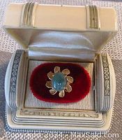 Ring displayed in white presentation box with red velvet insert