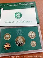 Front view of green protective case showing five 1996 US proof coins on green background and Certificate of Authenticity.