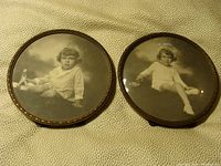 Both vintage round mahogany and brass photo frames shown side by side on fabric background