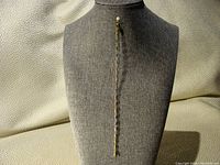 Full length photo of the two-tone gold bracelet displayed on a grey textured bust, showing the entire 7-inch length including clasp.