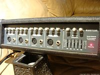 Front panel view of the Kustom KPM 4100 amplifier showing multiple volume, tone, and effects knobs as well as microphone and line input jacks.