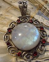 Front view showing large round labradorite cabochon with silver scrollwork and garnet stones.
