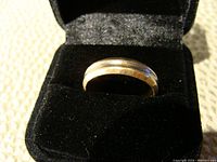 Side view of the two-tone gold ring in a black jewelry box showing the polished finish and subtle white gold center band.