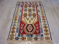 Full view of woven carpet showing geometric native design and fringed edge, photographed on light floor.