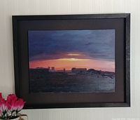 Framed oil painting showing city skyline during sunset with dark oak shadow box frame