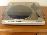 Front view with closed transparent dust cover showing entire Pioneer PL-4 turntable on wooden surface.