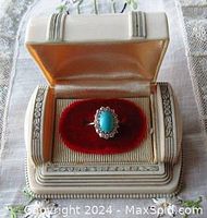Ring displayed in white and gold-tone presentation box with red velvet insert, showing overall appearance