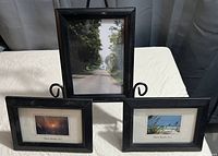 Three framed photographic prints arranged on a white surface: one vertical and two horizontal orientation. Two horizontal prints labeled 'Outer Banks, N.C.'; vertical shows tree-lined road.