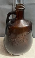 Front view of antique amber glass bottle with 'Goodenhams ESTD 1832' embossing and handle