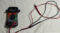 Full view of the Equus 4320 digital multimeter with red and black test leads placed on a light-colored cloth surface.
