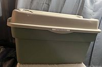 Large green Rubbermaid storage tote with beige lid showing two cracks.
