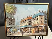 Oil painting showing an urban street scene with buildings and pedestrians, signed by Robert, framed in gold