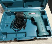 Makita corded drill and electric charger housed in teal hard plastic carrying case