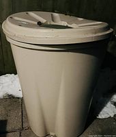 Full view of beige plastic rain barrel with lid, showing overall condition and design details.