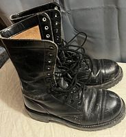 Side view of one black steel toe boot showing leather material and padded inside.