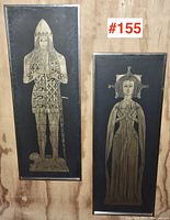 Overview of both framed brass rubbings side by side mounted on plywood background