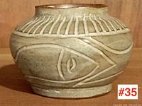 Front view of small pottery vase showing scraffito fish design and rim details.