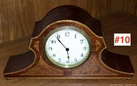 Front view of the Edwardian mantle clock showing mahogany inlaid wooden case and white clock face with black numbers and hands.