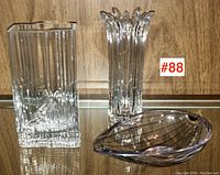 Front view of the Kosta Boda bowl and the two clear glass MCM vases side by side on a shelf.