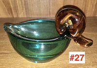 Side view showing entire green glass bowl body and amber-colored spiral head and beak of duck shape.