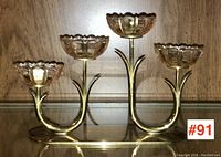 Front view of MCM Ystad-Metall brass and glass candleholder with two flower-shaped glass cups on brass arms and an oval brass base.