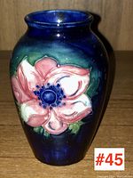 Front view of Moorcroft vase showing large pink flower on dark blue background.