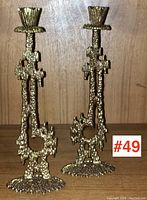 Frontal view of both cast brass Brutalist candlesticks side by side on wooden shelf