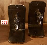 Pair of vintage 1930s horse head bookends, dark metal with beveled edges and detailed horse heads mounted on the backing plate. Positioned standing upright on a wooden surface.