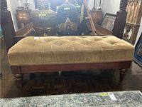Front view of the beige/gold tufted upholstered bench, showing the full rectangular seat and wooden frame with turned legs.