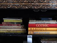 Books arranged on two shelves showing spines with titles of artistic styles and fantasy themes, 16 books total