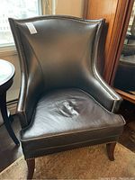Front three-quarter view of chair showing overall shape, upholstery, nailhead trim and legs