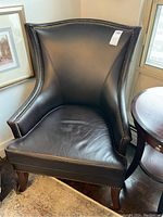 Full front view of dark brown leather wingback chair with nailhead trim