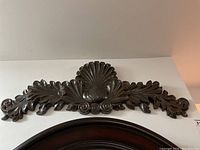 Full view of one carved wood scroll showing overall shape and design.